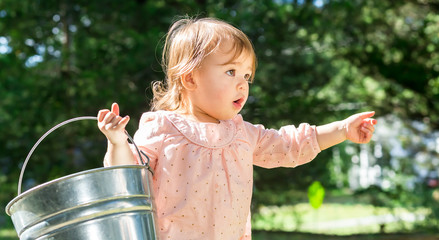 Wall Mural - Happy little toddler girl playing outside on a bright day