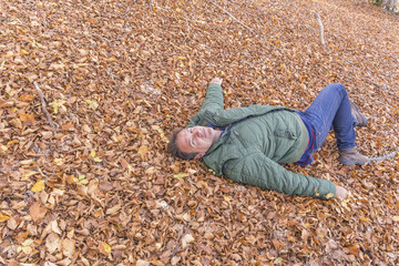 man lying on fallen autumn leaves