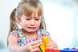 © karelnoppe - Unhappy little girl playing with wooden blocks.