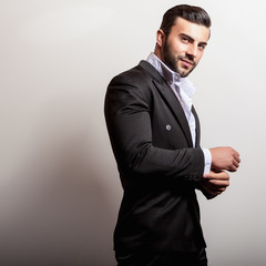 Elegant young handsome man in classic black costume. Studio fashion portrait.
