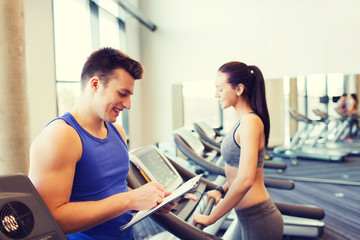 Canvas Print - happy woman with trainer on treadmill in gym