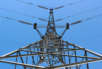 High voltage post or power transmission line tower on blue sky