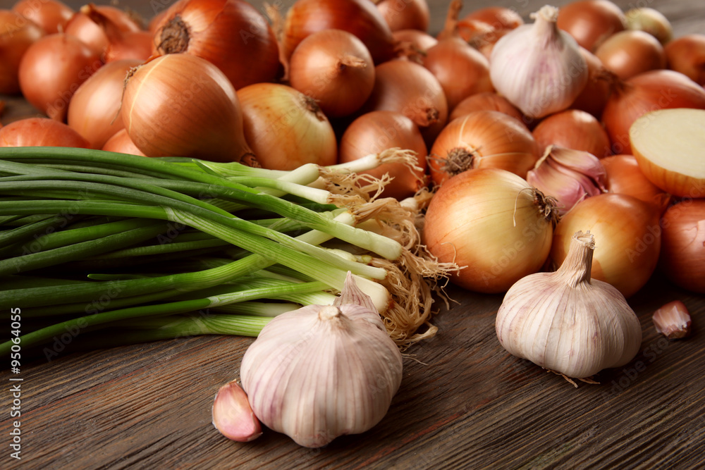 Fresh different onions with garlic on wooden background