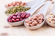 Assortment of beans and lentils in wooden spoon on wooden backgr