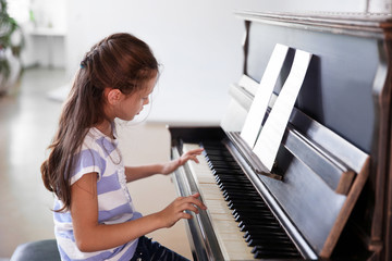 Wall Mural - Cute little girl studding to play piano