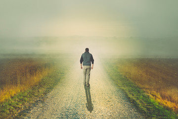 Wall Mural - Man walking to the light on a dirt road