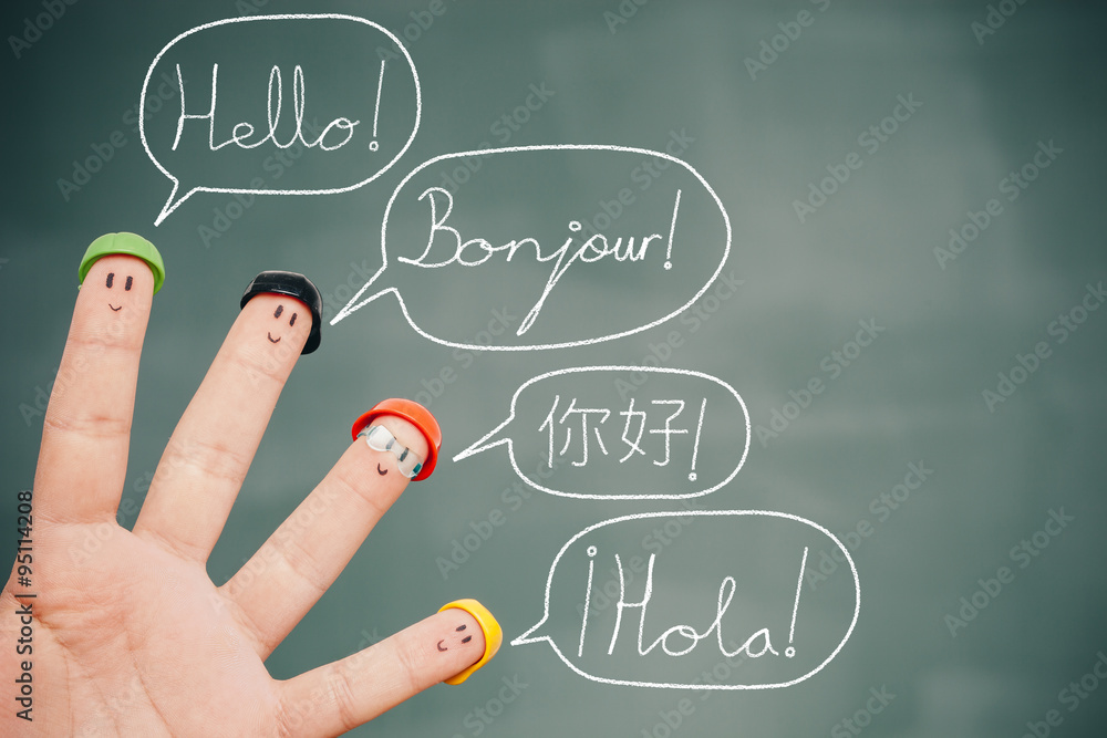 Fotografiet Four smiley fingers on a blackboard saying hello in English, French, Chinese and Spanish