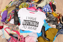 Big Pile Of Clothes Thrown On The Ground With A T-shirt Saying Nothing To Wear. Close Up On A Untidy Cluttered Wardrobe With Colorful Clothes And Accessories, Many Clothes And Nothing To Wear.
