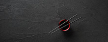 Chopsticks And Bowl With Soy Sauce On Black Stone Background