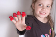 Little Girl Showing Off Her Hand With Raspberries On Each Finger