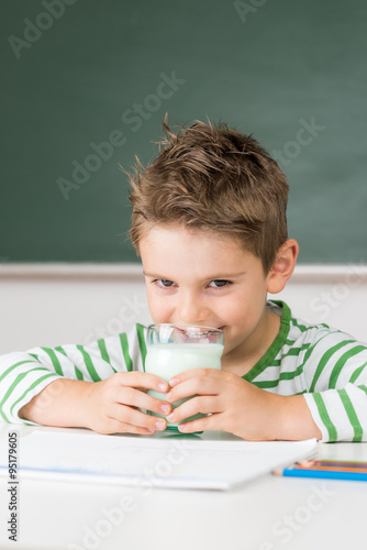Fototapeta na wymiar Kleiner Junge trinkt ein Glas Milch in der Schule