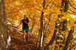 young woman in skirt running fast in the autumn forest with rock