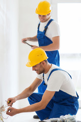 Canvas Print - builders with tablet pc and fixing wiring indoors