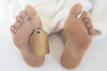 Naked Feet  In Bed With Wooden Tag
