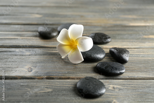 Naklejka na kafelki White plumeria flower with pebbles on wooden background