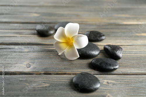 Fototapeta na wymiar White plumeria flower with pebbles on wooden background