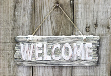 Rustic Wood Welcome Sign With Snow Hanging On Door