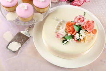 Wall Mural - Cake with sugar paste flowers and cupcakes, on light background