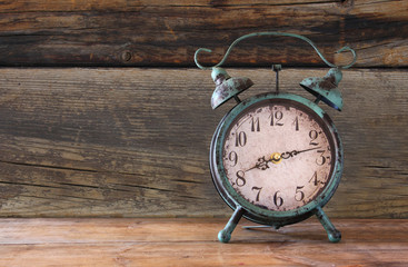 Wall Mural - image of vintage alarm clock on wooden table in front of wooden background. retro filtered
