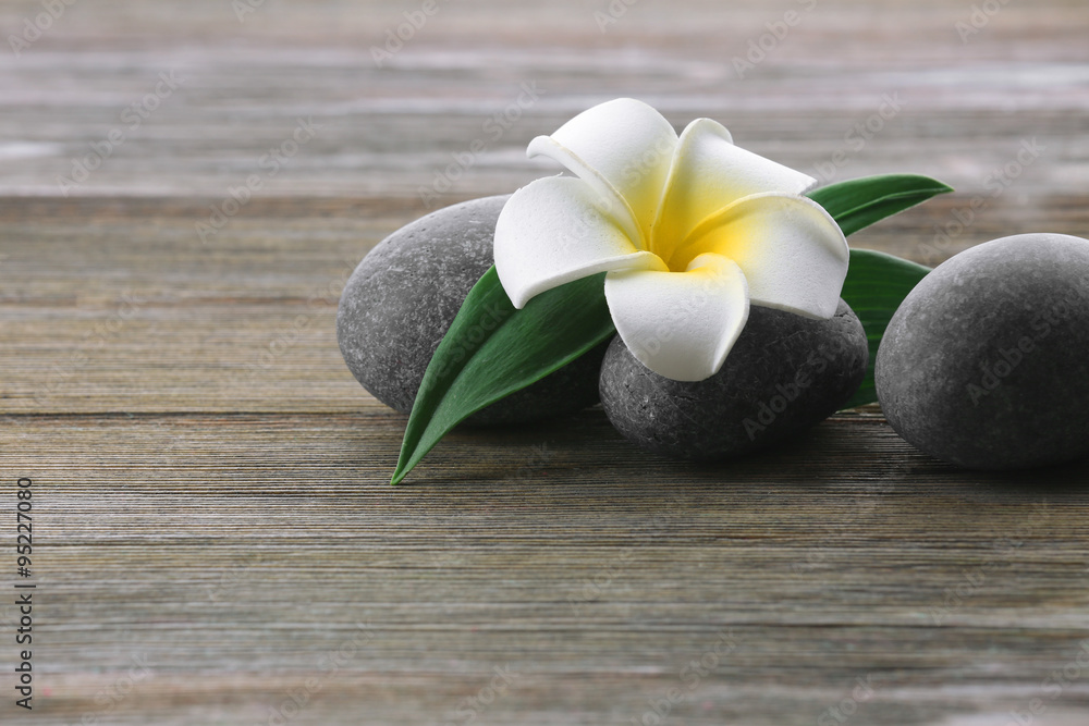 Spa stones with flower on wooden background