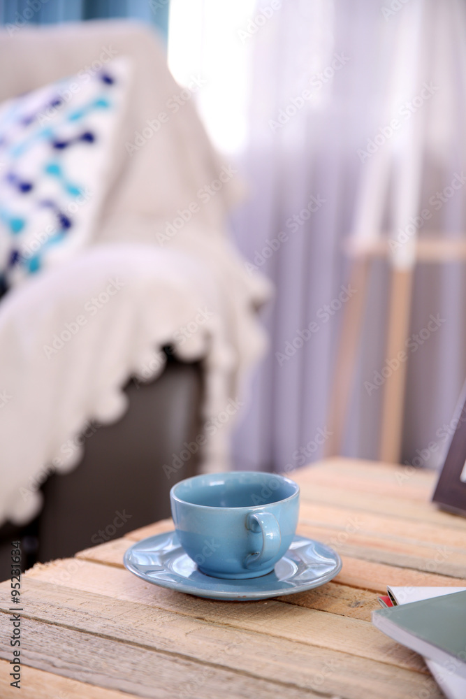 Cup with hot drink on coffee table, on home interior background