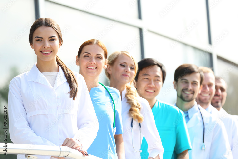 Smiling medics team standing in a row near the clinic