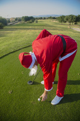 Wall Mural - Santa Claus on a golf course takes the ball