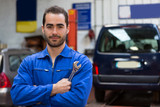 Fototapeta  - Young attractive mechanic working at the garage