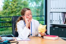 Young Female  Doctor With Piggy Bank