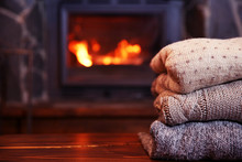 Knitted Clothes On Table On Fireplace Background