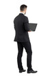 © sharplaninac - Rear view of young man in suit using laptop.  Full body length portrait isolated over white studio background.