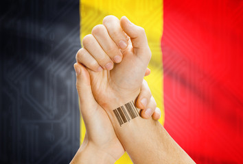 Barcode ID number on wrist and national flag on background - Belgium