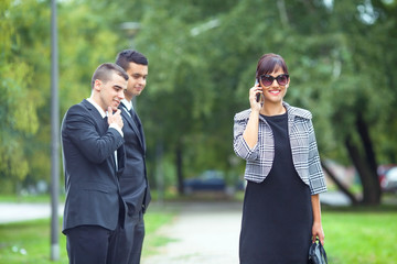 Two young businessmen checking out new attractive coworker passing by on the street