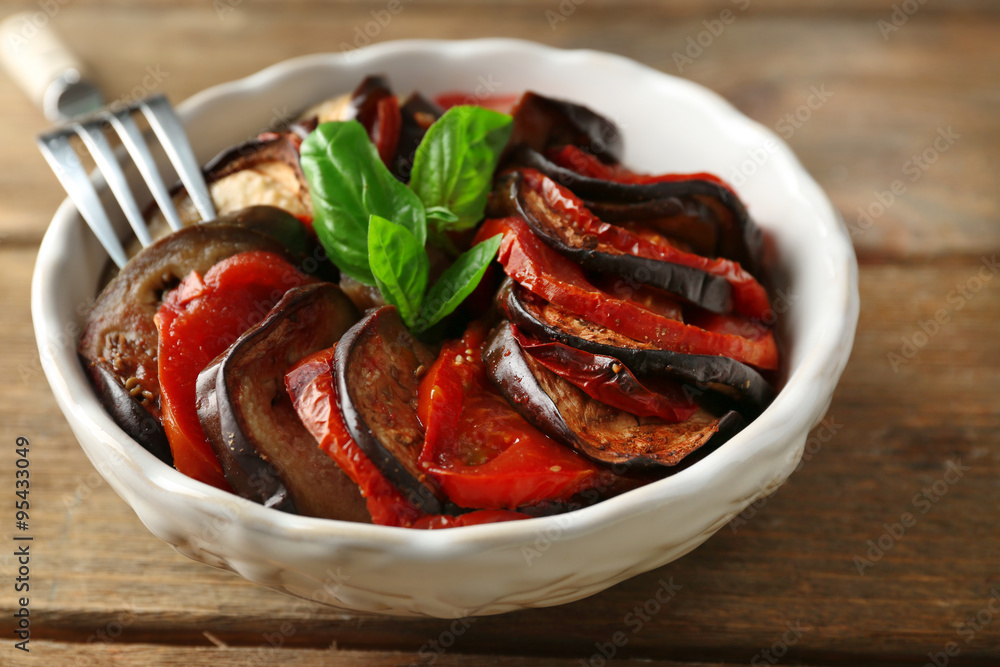 Ratatouille in bowl, on wooden table background