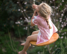 Girl Sitting On A Swing In Garden