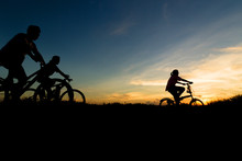 Silhouette Of Family Cycling At Sunset