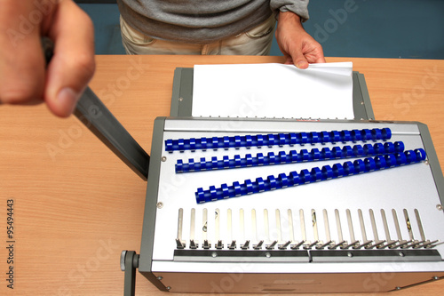 Fotografia, Obraz male man binding pages at table in paper store