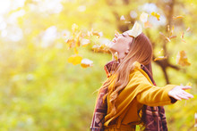 Beautiful Young Woman Throwing Leaves In A Park, Enjoying 