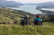 Two men on the top of hill looking  at harbour, view from behind