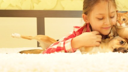 Canvas Print - Cute little girl playing with a dog and a cat lying on the couch