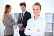 © rogerphoto - Pretty businesswoman in office with colleagues in the background