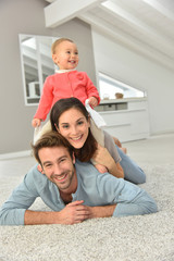 Wall Mural - Parents and baby girl laying on carpet,