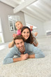 © goodluz - Parents and baby girl laying on carpet,