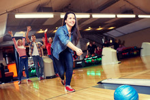 Happy Young Woman Throwing Ball In Bowling Club