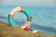 Beautiful Life Buoy In The Sand With Boat Toy On Unfocused Sea Background