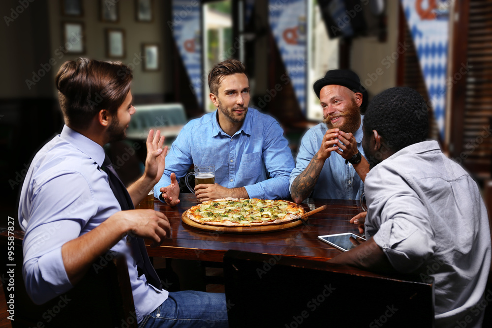 Young people eating pizza and drinking beer in cafe