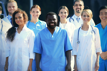 Wall Mural - Smiling team of young doctors against hospital entrance