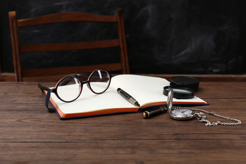 Poster - Opened notebook with eyeglasses and magnifying glass on wooden table