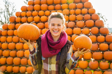 Wall Mural - Portrait of smiling woman holding pumpkins in autumn outdoors