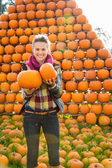portrait of smiling woman holding pumpkins in autumn outdoors